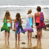 mermaid girls in mermaid tails swimming on the beach